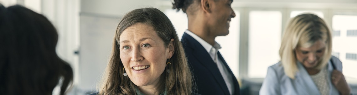 Flera personer st&aring;r och pratar med varandra p&aring; konferens